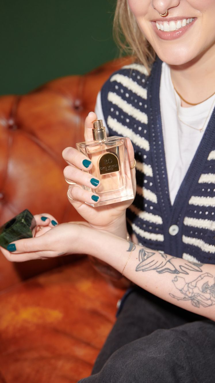 Kara McGrath spraying perfume on wrist with tattoos