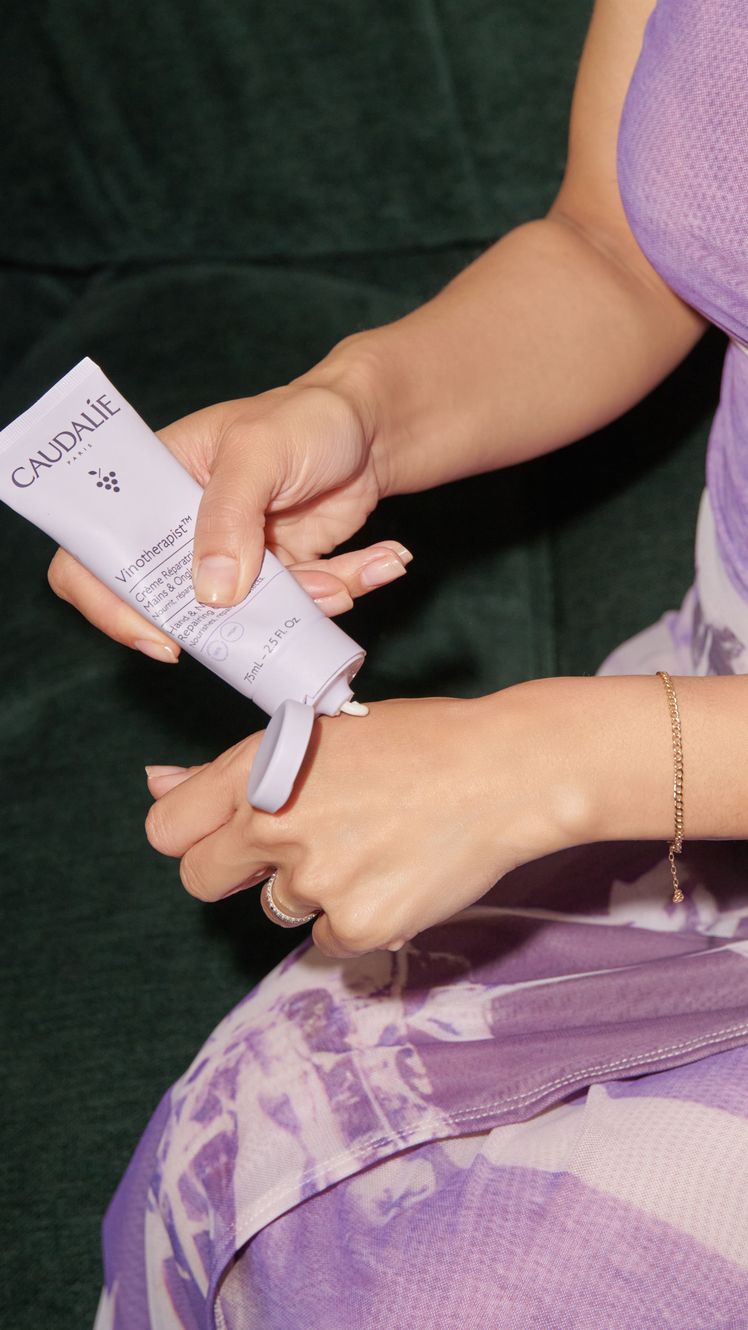 Caudalie Hand  Nail Cream being applied to hand of Shanna Shipin purple packaging
