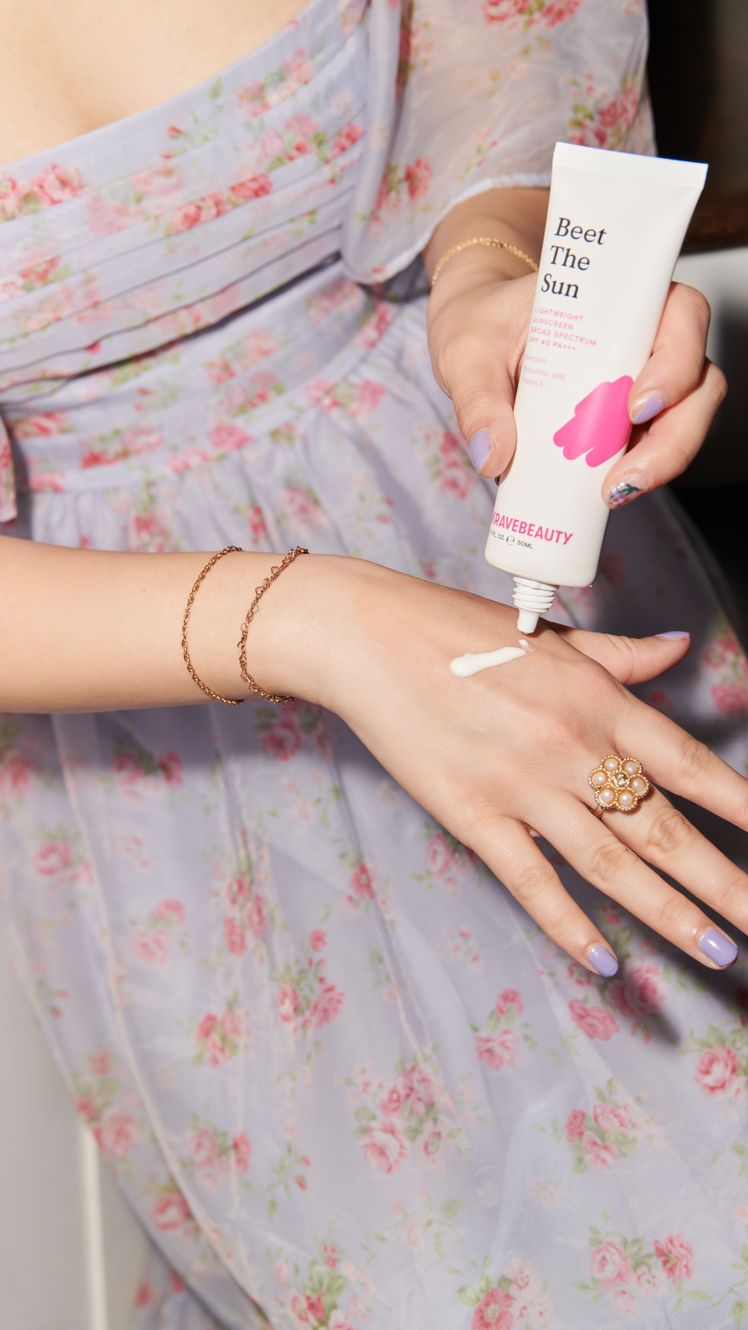 Sarah Han wearing lilac dress applying Krave Beauty Beet the Sun sunscreen to hand