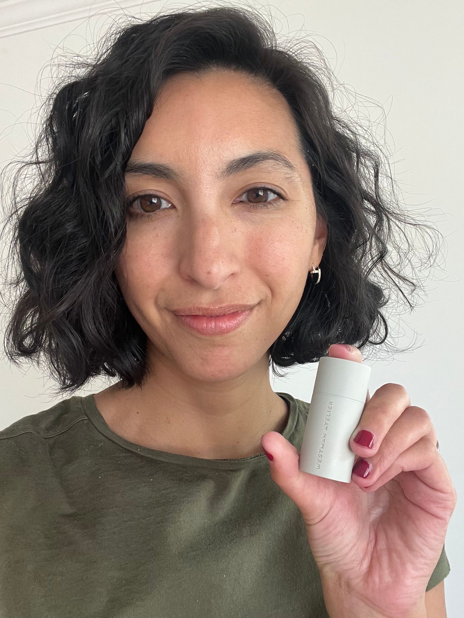 Woman smiling and holding a cream blush