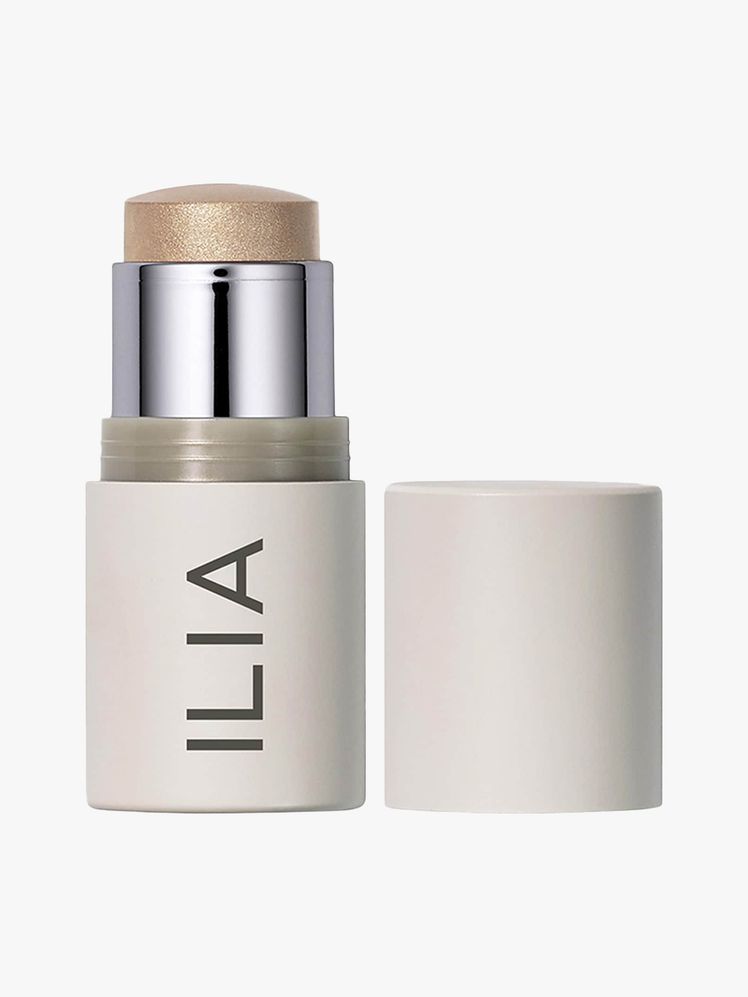 Ilia Illuminator beige twist up highlighter stick with cap to the side on light gray background