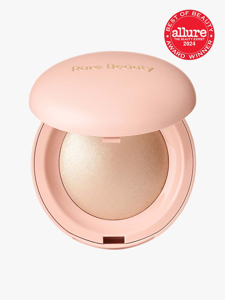 Rare Beauty Positive Light Silky Touch Highlighter round pink compact of champagne gold highlighter powder on a light...