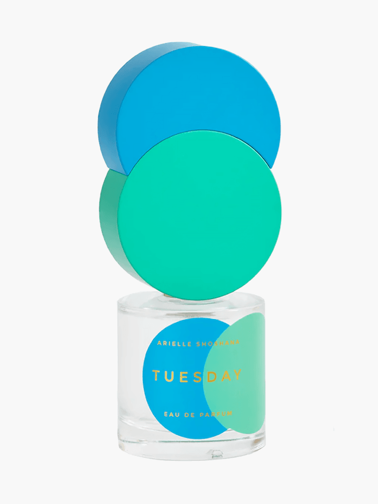 Tuesday perfume in branded clear bottle with blue and green decorative cap on light gray background